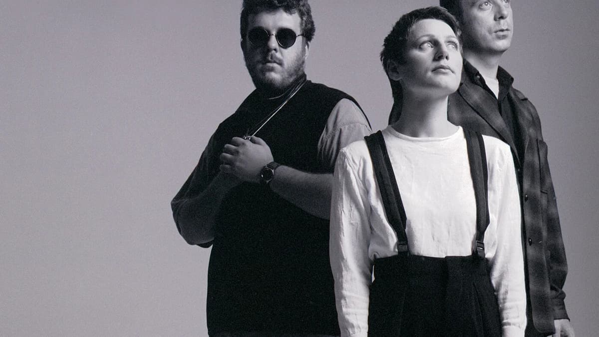 Black and white portrait of the Cocteau Twins: Robin Guthrie in dark glasses, Elizabeth Fraser in the centre and Simon Raymonde behind them