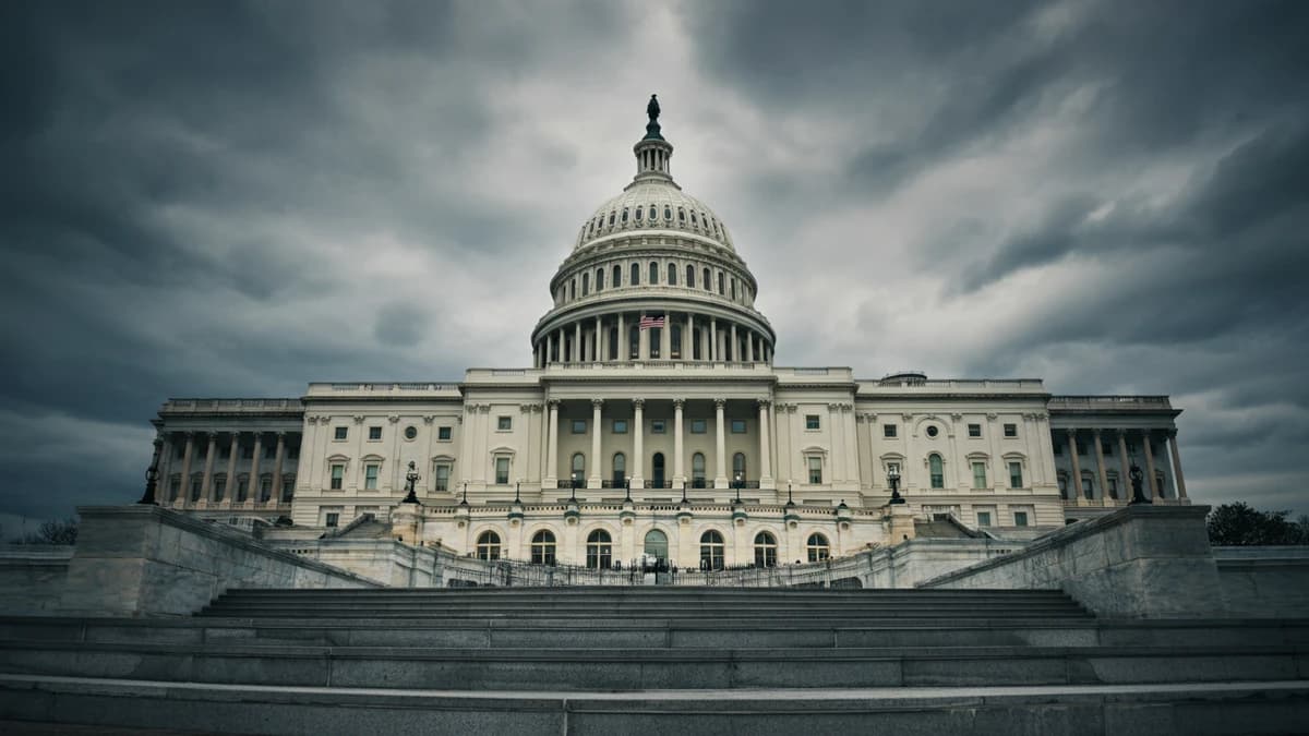 The U.S. Capitol Building shot from a low angle against a dramatic, overcast sky, representing a legislative battle.